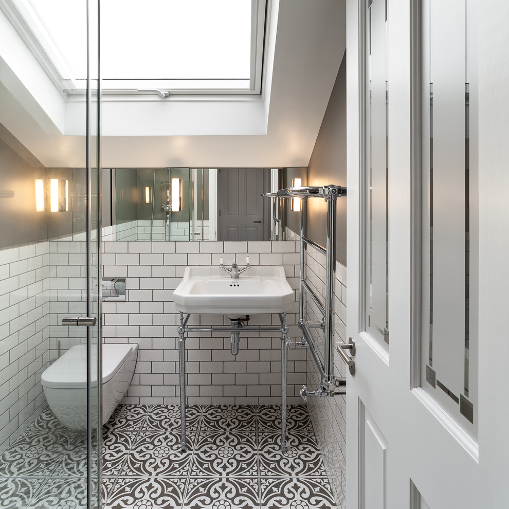 This is an example of a small traditional bathroom in London with a wall-mount toilet, white tile, grey walls, ceramic floors, multi-coloured floor, a console sink and subway tile.