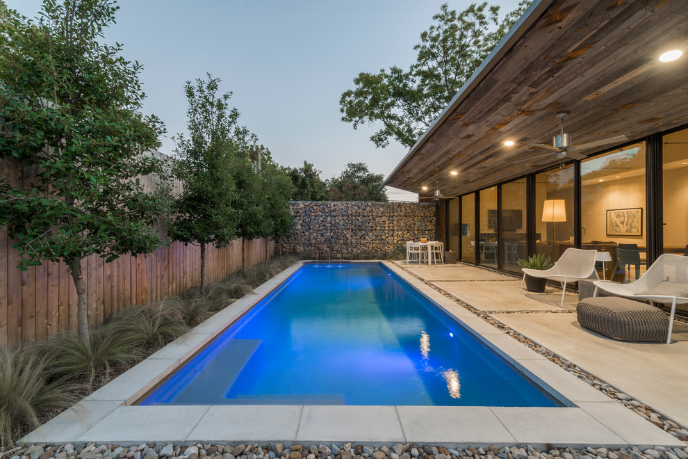 This is an example of a small industrial backyard rectangular lap pool in Dallas with concrete slab and a water feature.