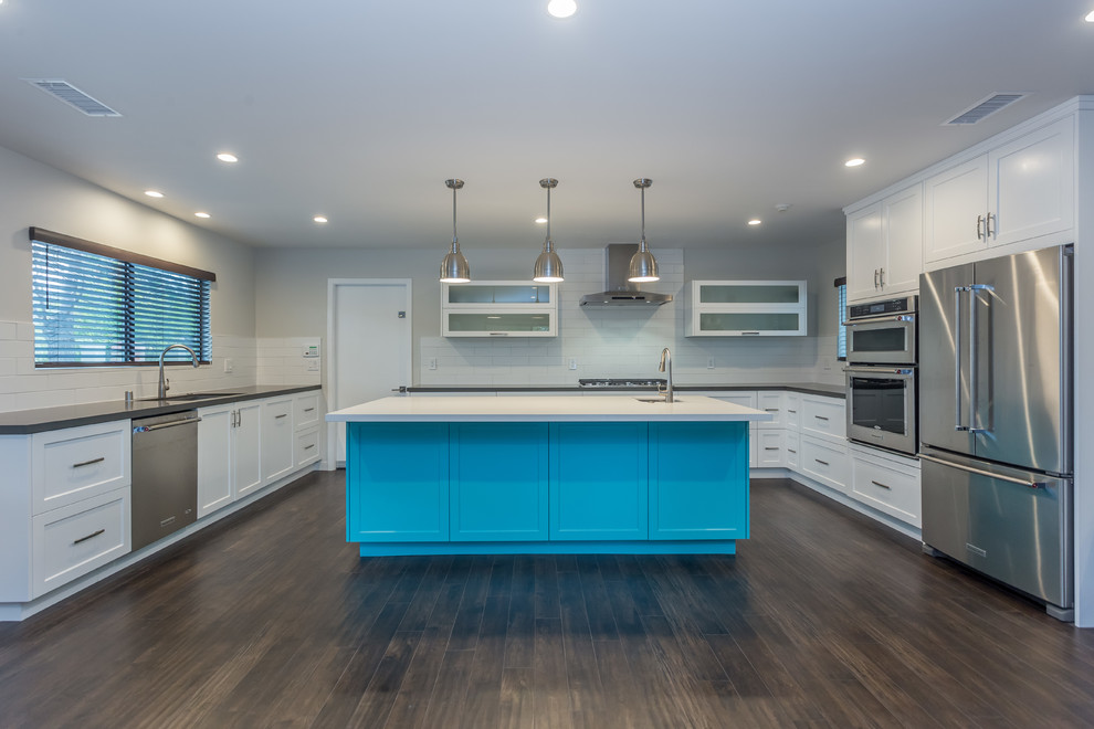 This is an example of a large contemporary u-shaped open plan kitchen in Los Angeles with a single-bowl sink, shaker cabinets, white cabinets, quartzite benchtops, white splashback, subway tile splashback, stainless steel appliances, dark hardwood floors and with island.