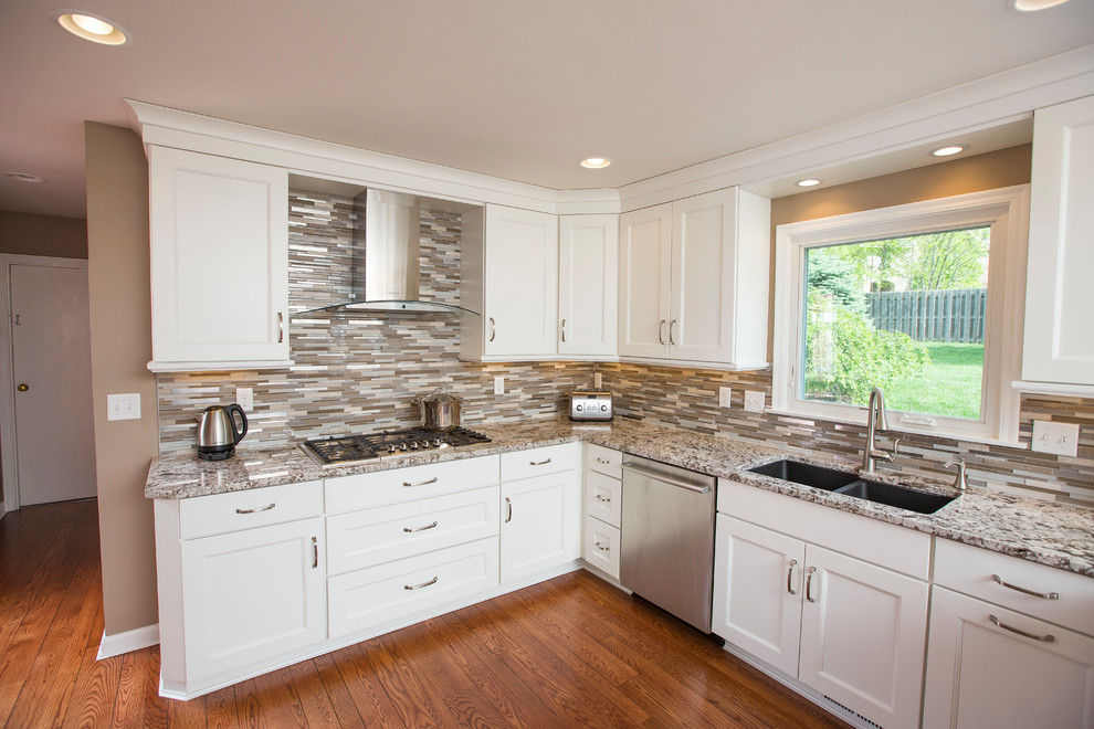 Inspiration for a large transitional u-shaped medium tone wood floor and brown floor eat-in kitchen remodel in Cincinnati with an undermount sink, shaker cabinets, white cabinets, granite countertops, multicolored backsplash, matchstick tile backsplash, white appliances, a peninsula and beige countertops