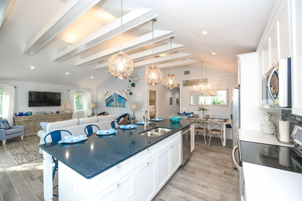 Design ideas for a beach style eat-in kitchen in Tampa with an undermount sink, shaker cabinets, white cabinets, quartzite benchtops, blue splashback, glass tile splashback, stainless steel appliances, porcelain floors, with island, grey floor and blue benchtop.