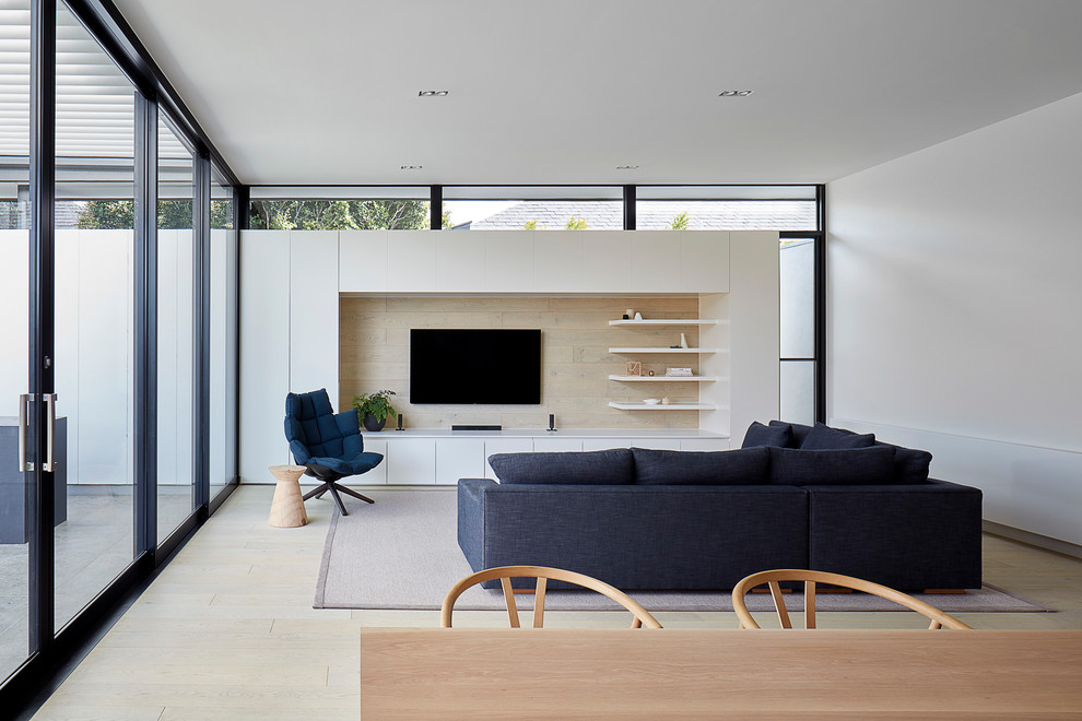 Inspiration for a contemporary formal open concept living room in Melbourne with white walls, light hardwood floors, a wall-mounted tv and beige floor.