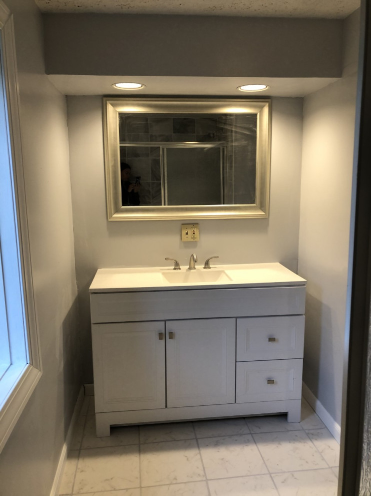 Large modern ensuite bathroom in Columbus with white cabinets, a shower/bath combination, ceramic flooring, white floors, a sliding door, white worktops, a single sink and a freestanding vanity unit.