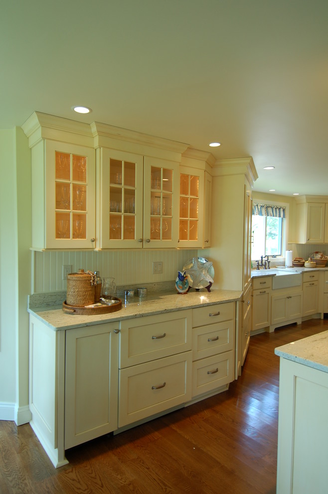 Photo of a mid-sized beach style eat-in kitchen in Boston with a farmhouse sink, recessed-panel cabinets, yellow cabinets, granite benchtops, white splashback, panelled appliances, medium hardwood floors and with island.
