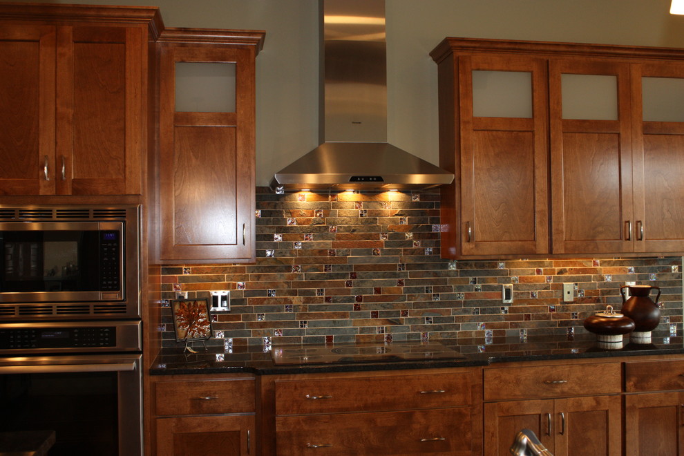Open concept kitchen - mid-sized transitional l-shaped medium tone wood floor open concept kitchen idea with an undermount sink, recessed-panel cabinets, medium tone wood cabinets, granite countertops, multicolored backsplash, mosaic tile backsplash, stainless steel appliances and an island