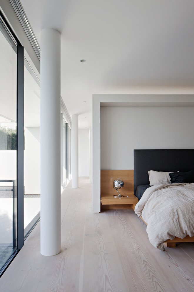 This is an example of a modern master bedroom in Melbourne with white walls, light hardwood floors and beige floor.