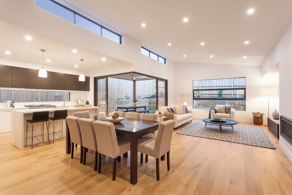 Large contemporary open plan dining in Melbourne with white walls, light hardwood floors, a standard fireplace and a metal fireplace surround.