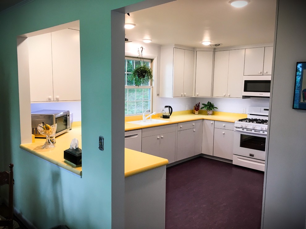 This is an example of a mid-sized midcentury u-shaped separate kitchen in New York with an undermount sink, flat-panel cabinets, white cabinets, laminate benchtops, white splashback, white appliances, linoleum floors and purple floor.