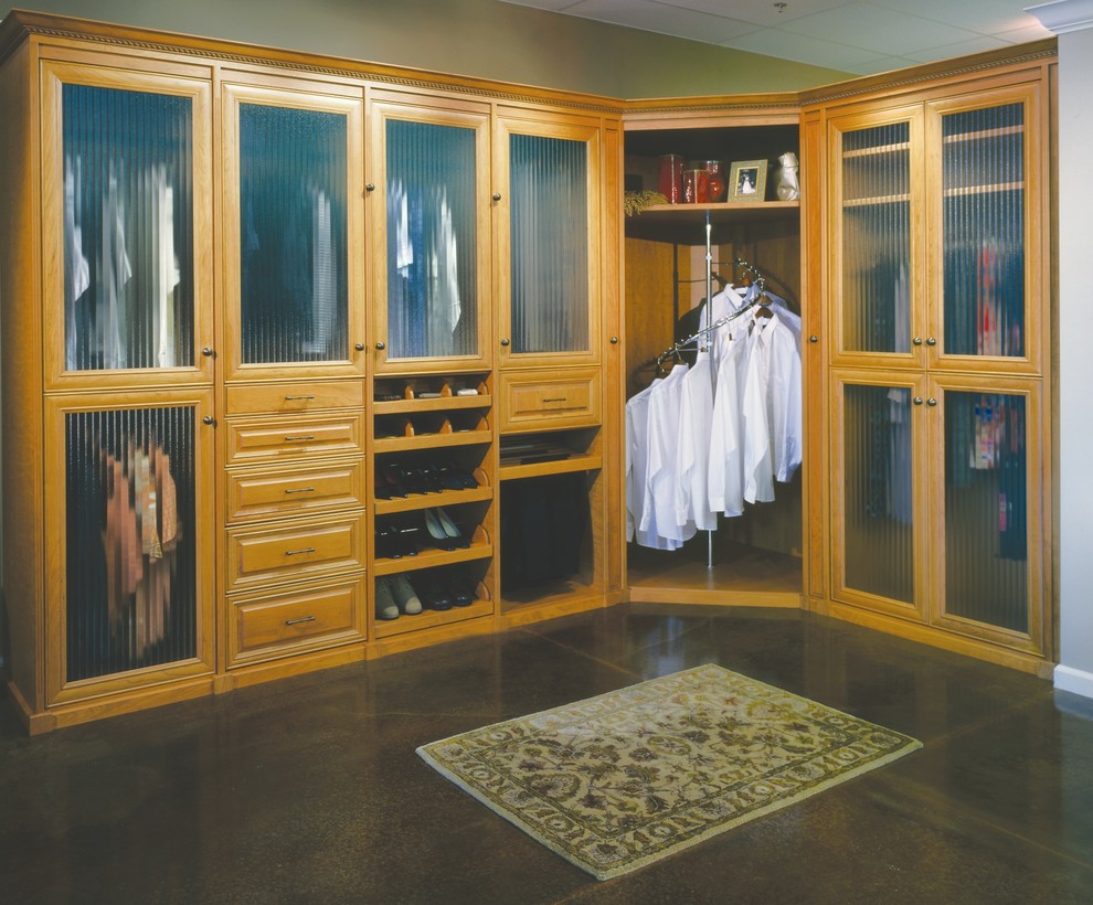Mid-sized traditional men's walk-in wardrobe in Minneapolis with glass-front cabinets, light wood cabinets and concrete floors.