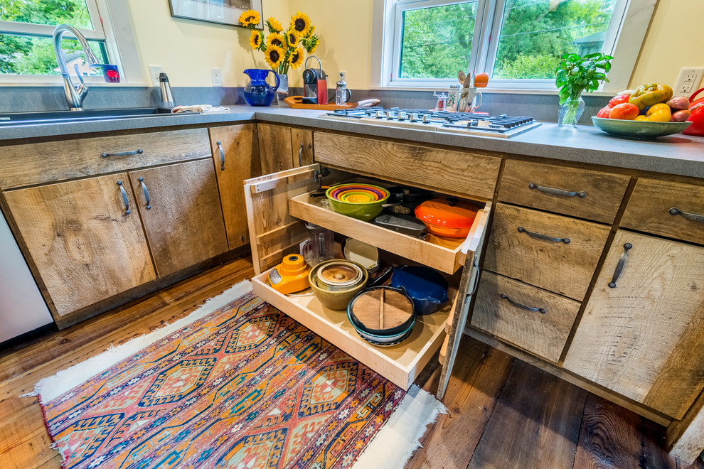 This is an example of a mid-sized country kitchen in Detroit with a drop-in sink, flat-panel cabinets, distressed cabinets, medium hardwood floors and concrete benchtops.