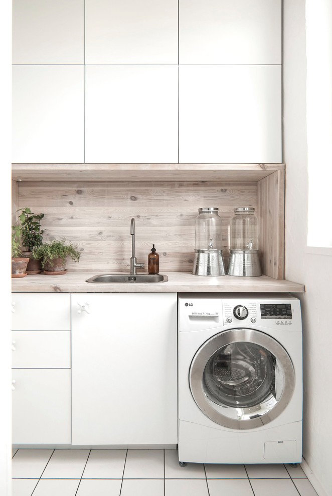 Design ideas for a small contemporary single-wall utility room in Saint Petersburg with flat-panel cabinets, white cabinets, wood benchtops, white walls, ceramic floors, white floor, beige benchtop and a single-bowl sink.