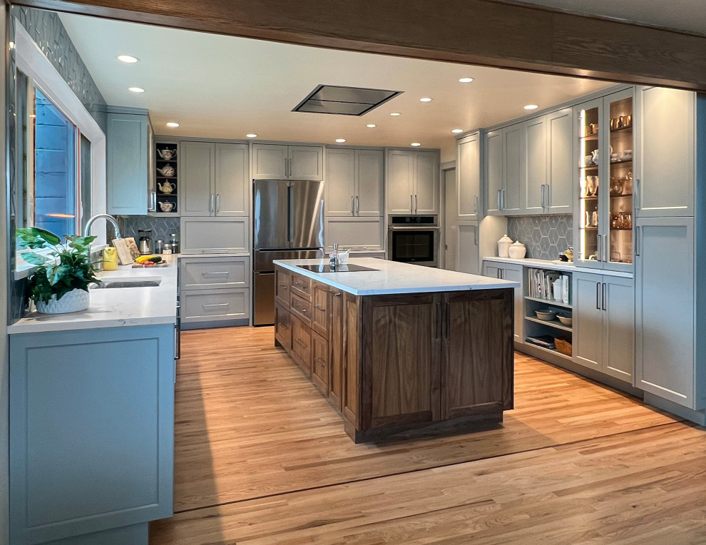Example of a large transitional u-shaped medium tone wood floor and brown floor eat-in kitchen design in Seattle with an undermount sink, shaker cabinets, blue cabinets, quartz countertops, blue backsplash, ceramic backsplash, stainless steel appliances, an island and white countertops
