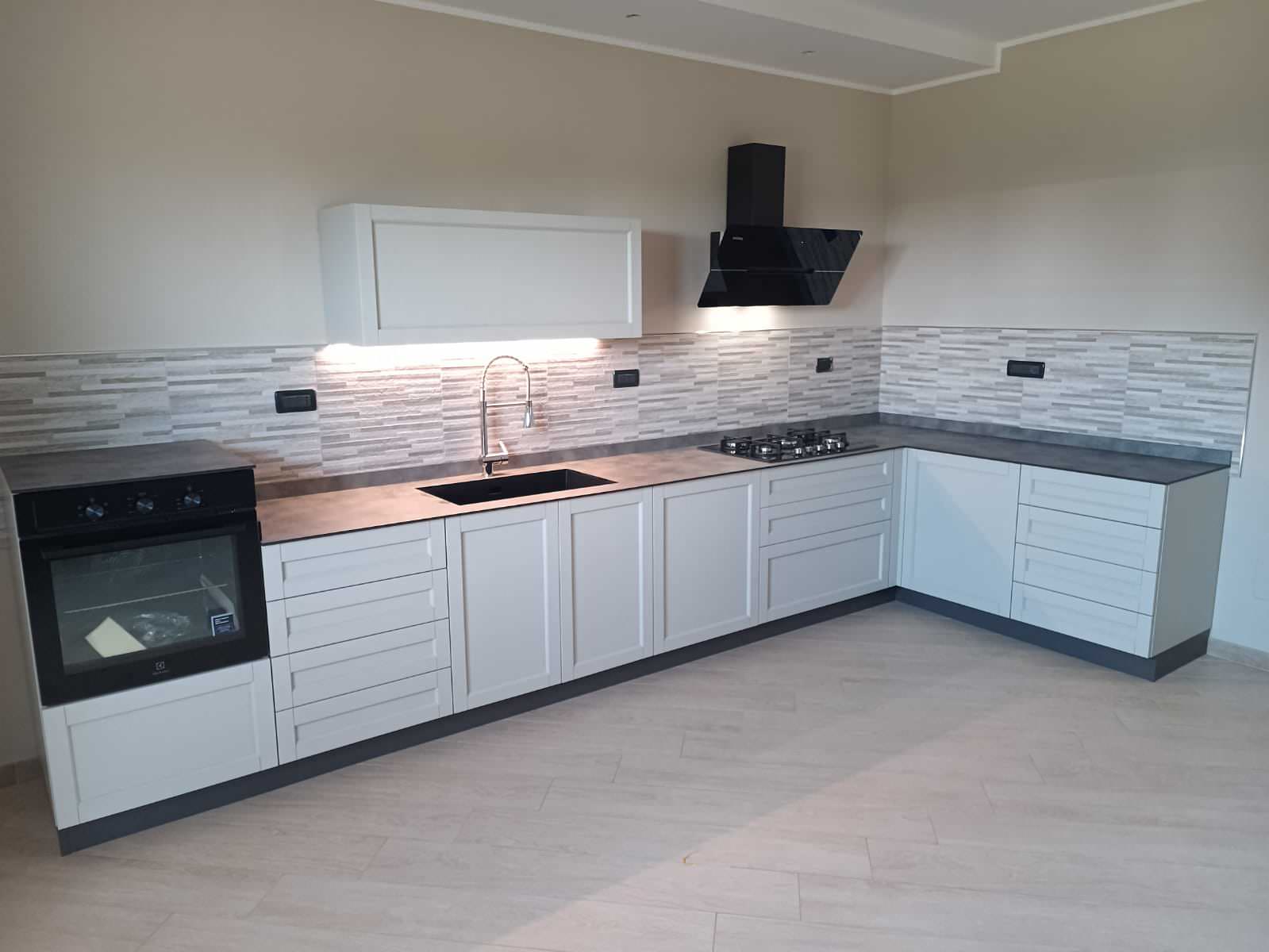 Cucina con anta Telaio in Frassino massello con maniglia integrata finitura Laccato Corda e Top in HPL finitura Cemento. Lavello un vascone sottotop in Keratek Nero. Frontalmente colonnine dispensa ef