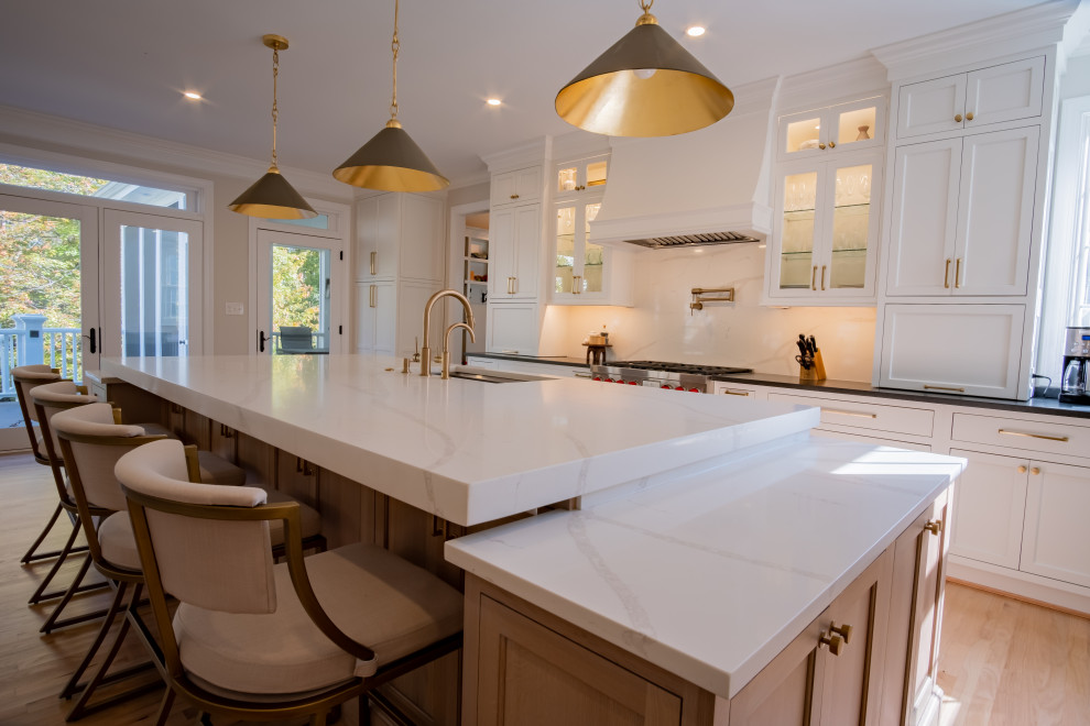 Design ideas for a large traditional l-shaped eat-in kitchen in DC Metro with an undermount sink, beaded inset cabinets, white cabinets, quartz benchtops, white splashback, engineered quartz splashback, stainless steel appliances, light hardwood floors, with island, brown floor, white benchtop and wallpaper.
