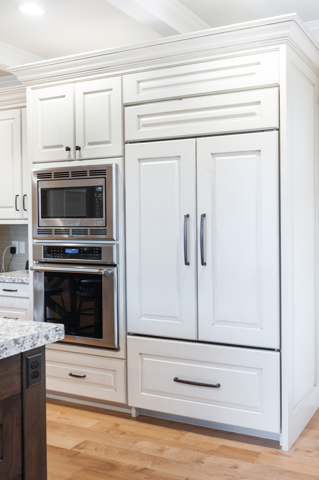 Design ideas for a transitional kitchen in Salt Lake City with raised-panel cabinets, white cabinets, granite benchtops, stainless steel appliances, medium hardwood floors and with island.