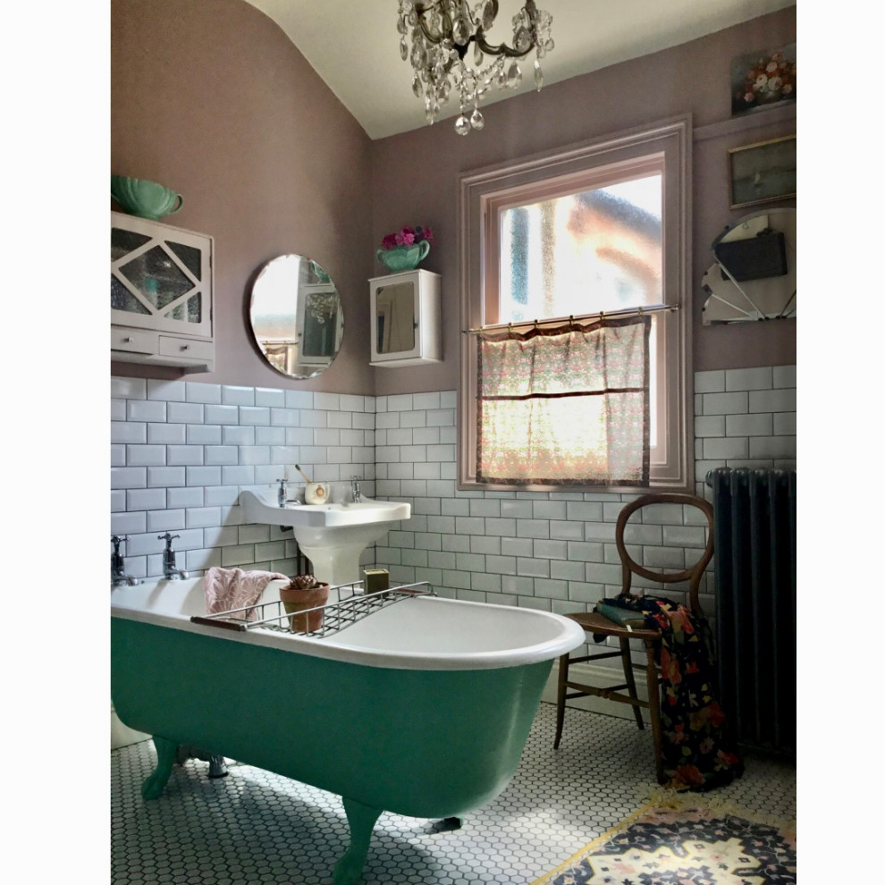 他の地域にあるお手頃価格の中くらいなトラディショナルスタイルのおしゃれな浴室 (猫足バスタブ、白いタイル、ピンクの壁、ペデスタルシンク、白い床、独立型洗面台) の写真