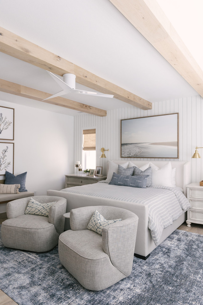Example of a beach style light wood floor, beige floor and exposed beam bedroom design in San Diego with white walls