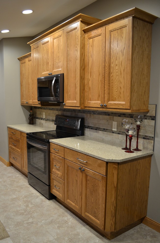 Example of a mid-sized transitional galley eat-in kitchen design with an undermount sink, flat-panel cabinets, medium tone wood cabinets, quartz countertops, beige backsplash, porcelain backsplash, stainless steel appliances and no island