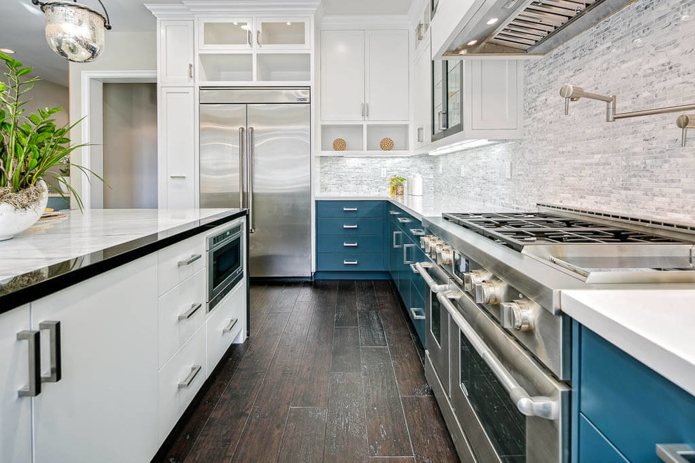 Beach style kitchen in Los Angeles with an undermount sink, glass-front cabinets, blue cabinets, grey splashback, stainless steel appliances, dark hardwood floors, with island and brown floor.