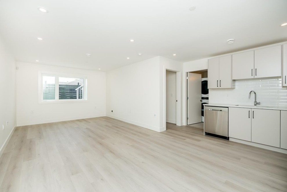 Example of a mid-sized transitional walk-out vinyl floor and beige floor basement design in Vancouver with white walls and no fireplace
