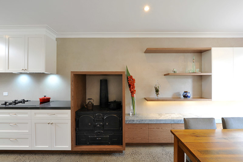 Photo of a transitional u-shaped eat-in kitchen in Melbourne with a farmhouse sink, shaker cabinets, white cabinets, quartz benchtops, porcelain splashback, stainless steel appliances, concrete floors and no island.