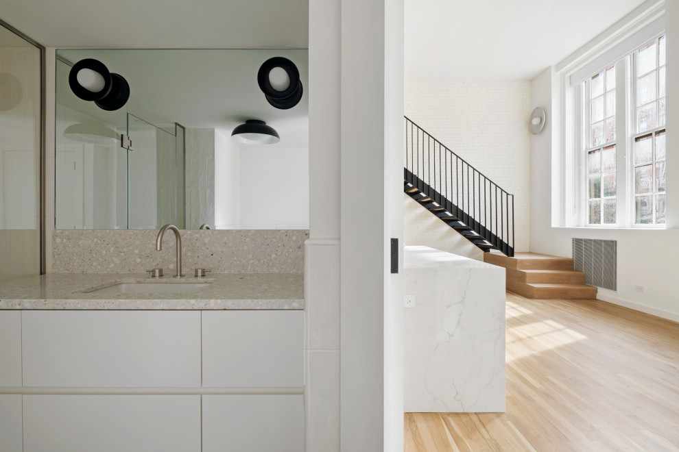 Exempel på ett mellanstort modernt beige beige en-suite badrum, med släta luckor, vita skåp, ett badkar i en alkov, en dusch/badkar-kombination, en vägghängd toalettstol, beige kakel, keramikplattor, vita väggar, klinkergolv i keramik, ett nedsänkt handfat, bänkskiva i terrazo, svart golv och dusch med gångjärnsdörr