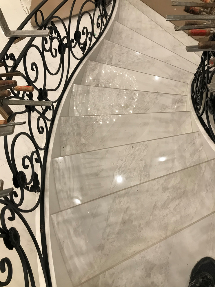 Foto di un'ampia scala curva vittoriana con parapetto in metallo, pedata in marmo, alzata in marmo e boiserie