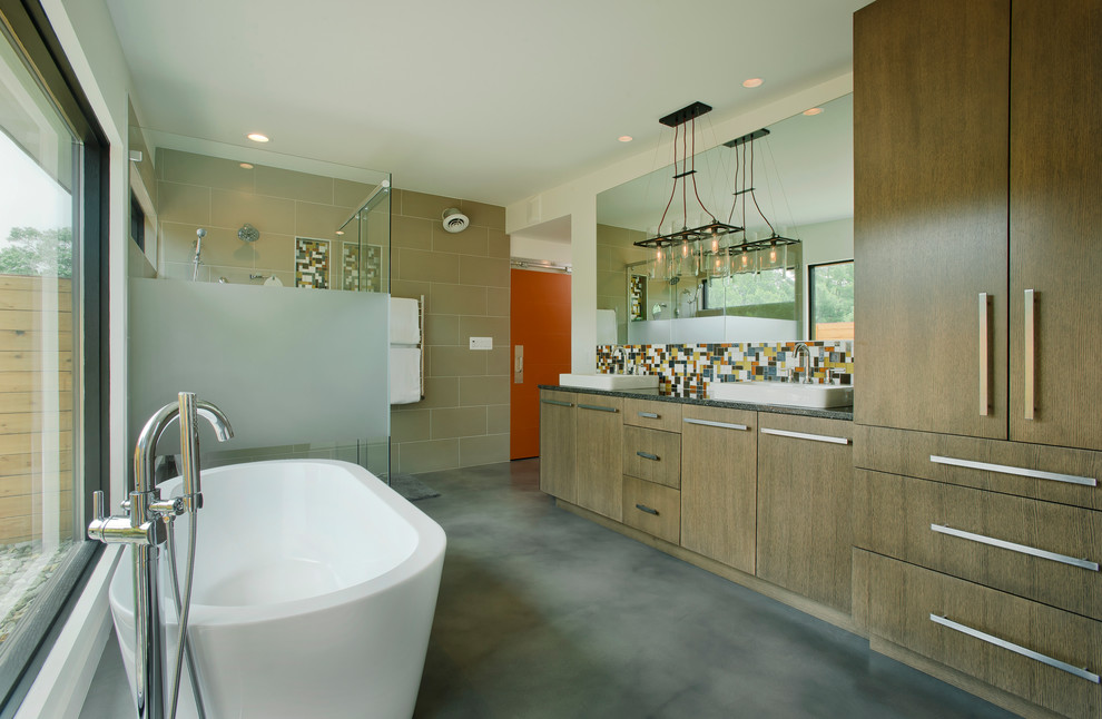Photo of a large contemporary master bathroom in Baltimore with a vessel sink, flat-panel cabinets, medium wood cabinets, engineered quartz benchtops, a freestanding tub, a corner shower, multi-coloured tile, ceramic tile, concrete floors, a two-piece toilet, beige walls, grey floor and a hinged shower door.