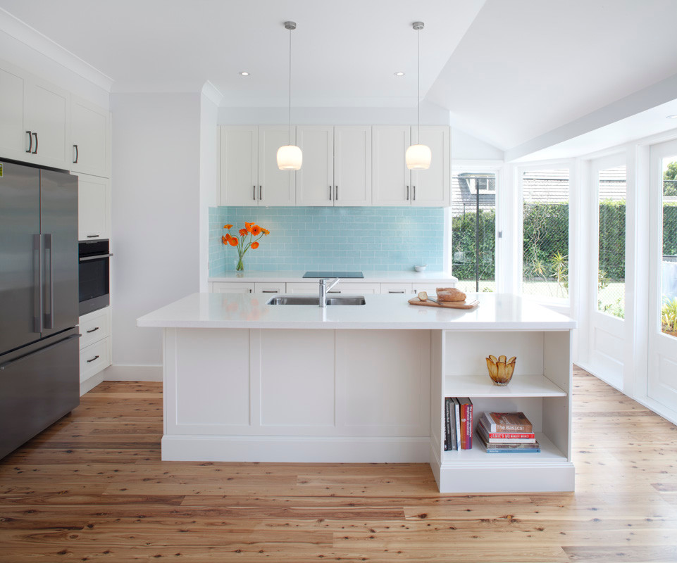 Photo of a large transitional l-shaped eat-in kitchen in Sydney with an undermount sink, shaker cabinets, white cabinets, quartz benchtops, blue splashback, ceramic splashback, stainless steel appliances, bamboo floors and with island.