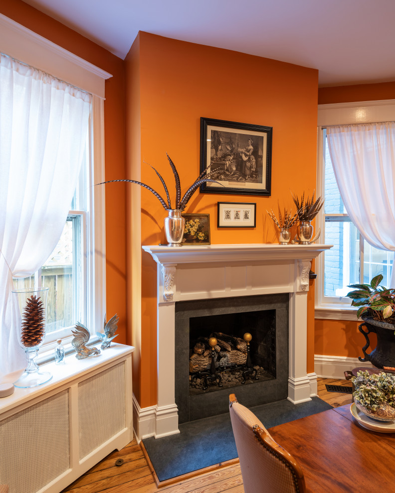 Пример оригинального дизайна: отдельная столовая среднего размера в классическом стиле с оранжевыми стенами, паркетным полом среднего тона, стандартным камином, фасадом камина из камня и коричневым полом