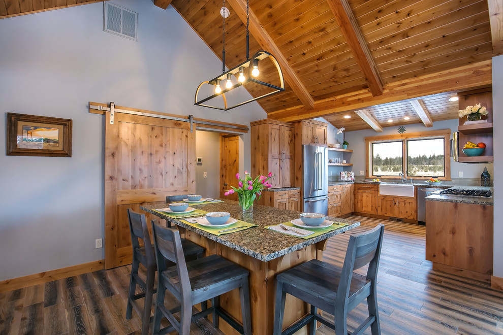 This is an example of a country u-shaped kitchen in Other with a farmhouse sink, shaker cabinets, medium wood cabinets, stainless steel appliances and with island.