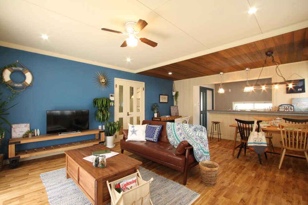 Beach style open concept living room in Other with multi-coloured walls, medium hardwood floors, a freestanding tv and brown floor.