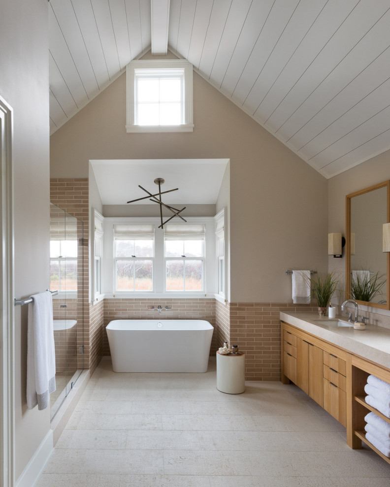 This is an example of a beach style bathroom in San Francisco with flat-panel cabinets, medium wood cabinets, a freestanding tub, brown tile, subway tile, beige walls, an undermount sink, beige floor, grey benchtops, a built-in vanity, vaulted and planked wall panelling.