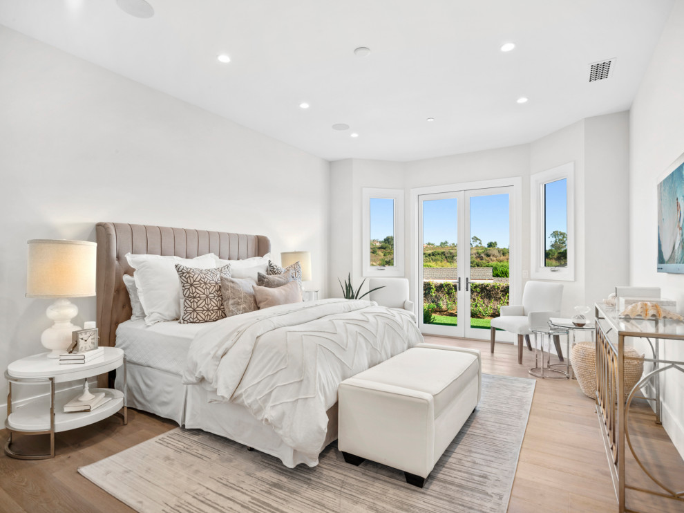 This is an example of a large transitional master bedroom in Orange County with white walls, light hardwood floors and beige floor.