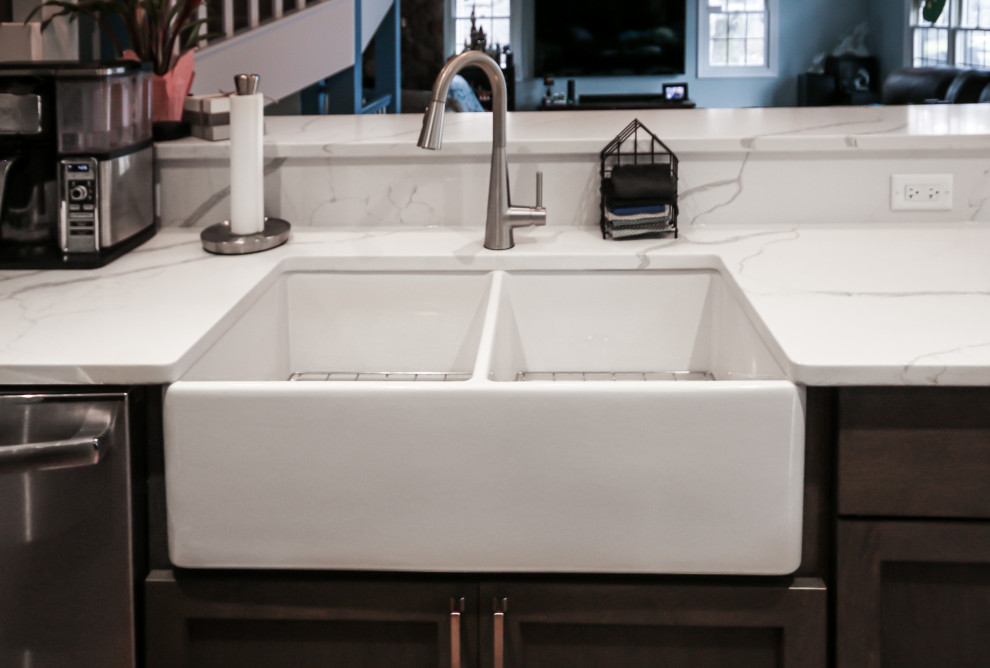 Large transitional u-shaped medium tone wood floor eat-in kitchen photo in Chicago with a farmhouse sink, shaker cabinets, dark wood cabinets, quartz countertops, white backsplash, quartz backsplash, stainless steel appliances, a peninsula and white countertops