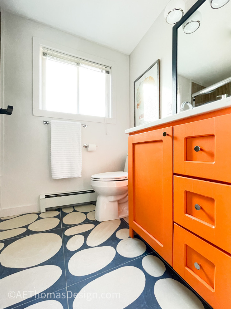 Photo of a small modern bathroom in Burlington with recessed-panel cabinets, orange cabinets, an alcove bath, a shower/bath combination, a two-piece toilet, white walls, ceramic flooring, a submerged sink, engineered stone worktops, blue floors, a sliding door, white worktops, a single sink and a freestanding vanity unit.