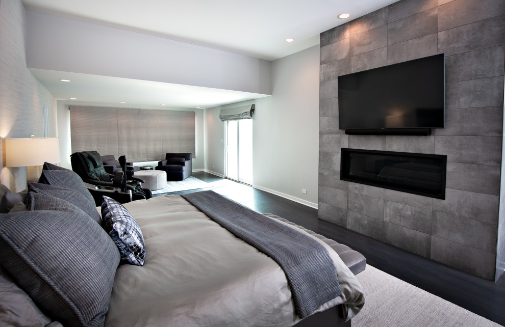 Großes Modernes Hauptschlafzimmer mit grauer Wandfarbe, dunklem Holzboden, Gaskamin, Kaminumrandung aus Stein, braunem Boden und Tapetenwänden in Chicago