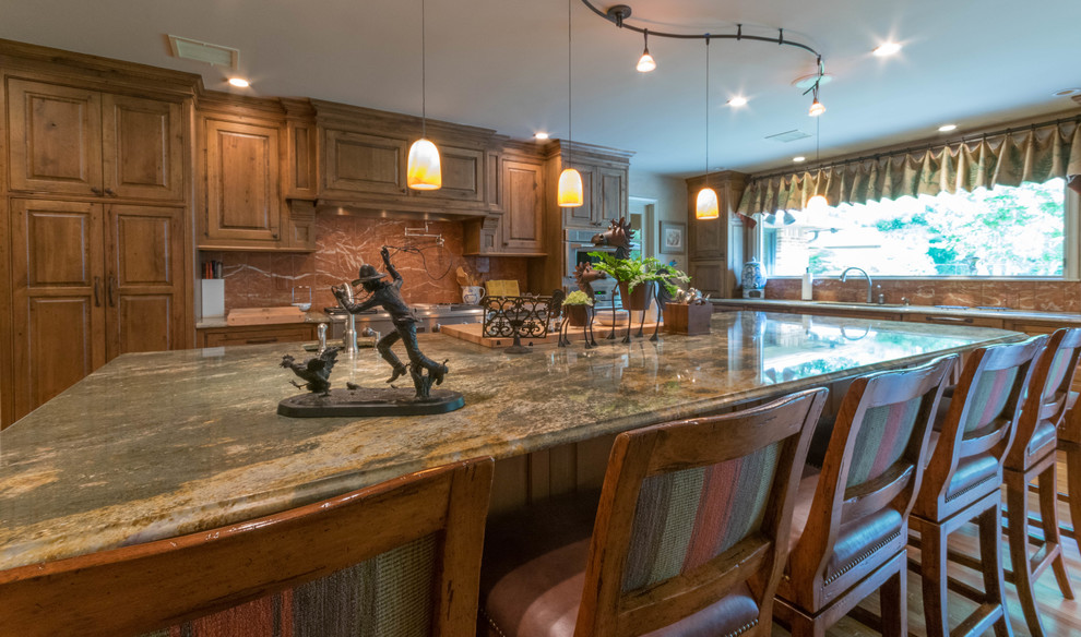 Large mountain style u-shaped light wood floor eat-in kitchen photo with an integrated sink, beaded inset cabinets, distressed cabinets, granite countertops, orange backsplash, stone slab backsplash, stainless steel appliances and an island