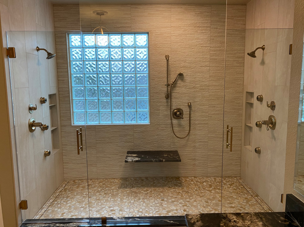 Inspiration for a large contemporary master bathroom in Austin with raised-panel cabinets, medium wood cabinets, an alcove shower, a two-piece toilet, beige tile, porcelain tile, brown walls, porcelain floors, an undermount sink, granite benchtops, beige floor, a hinged shower door, black benchtops, a shower seat, a double vanity and a built-in vanity.