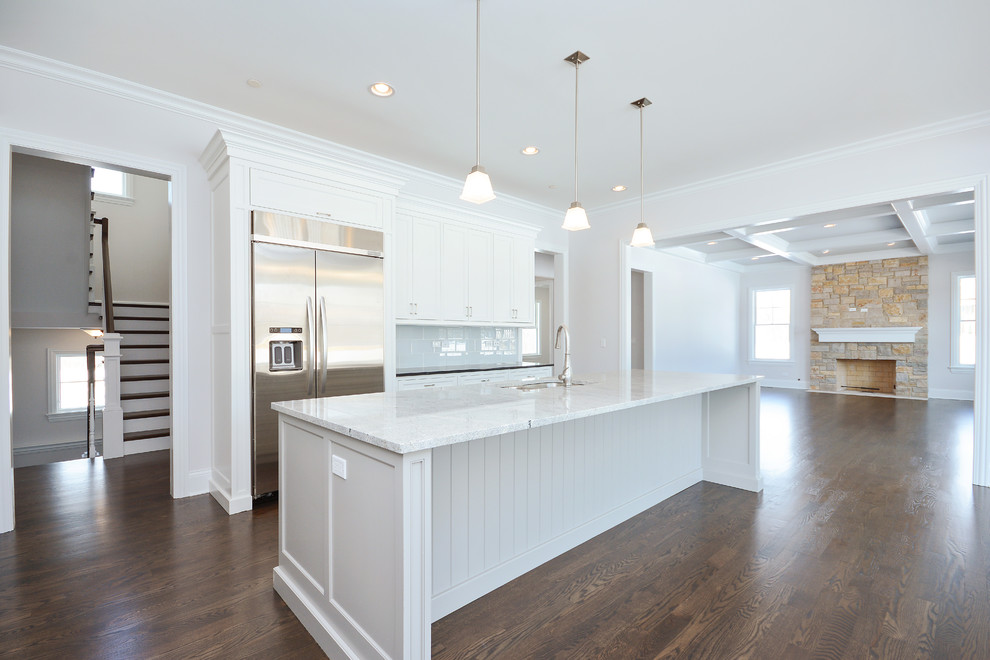 Inspiration for a large arts and crafts l-shaped open plan kitchen in Chicago with an undermount sink, recessed-panel cabinets, white cabinets, granite benchtops, grey splashback, subway tile splashback, stainless steel appliances, medium hardwood floors and with island.