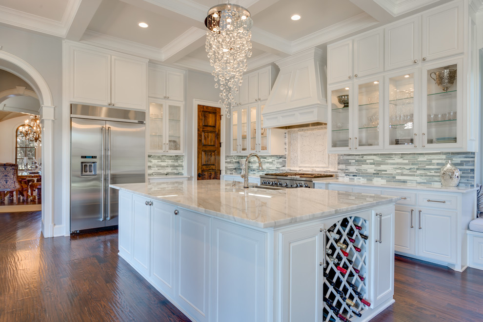 Traditional l-shaped kitchen in Dallas with a farmhouse sink, raised-panel cabinets, white cabinets, multi-coloured splashback, matchstick tile splashback, stainless steel appliances, dark hardwood floors and with island.