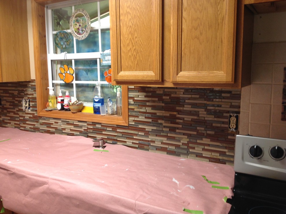 Eat-in kitchen - l-shaped eat-in kitchen idea with an undermount sink, flat-panel cabinets, brown backsplash, glass tile backsplash, stainless steel appliances and a peninsula