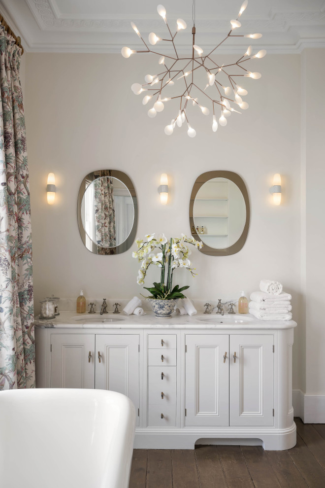 Inspiration for a traditional bathroom in London with recessed-panel cabinets, white cabinets, beige walls, dark hardwood flooring, a submerged sink, brown floors, white worktops, double sinks and a built in vanity unit.