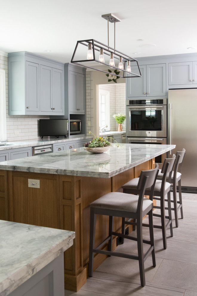 Enclosed kitchen - large transitional u-shaped porcelain tile and gray floor enclosed kitchen idea in Los Angeles with a drop-in sink, shaker cabinets, quartzite countertops, white backsplash, ceramic backsplash, stainless steel appliances, an island and gray countertops