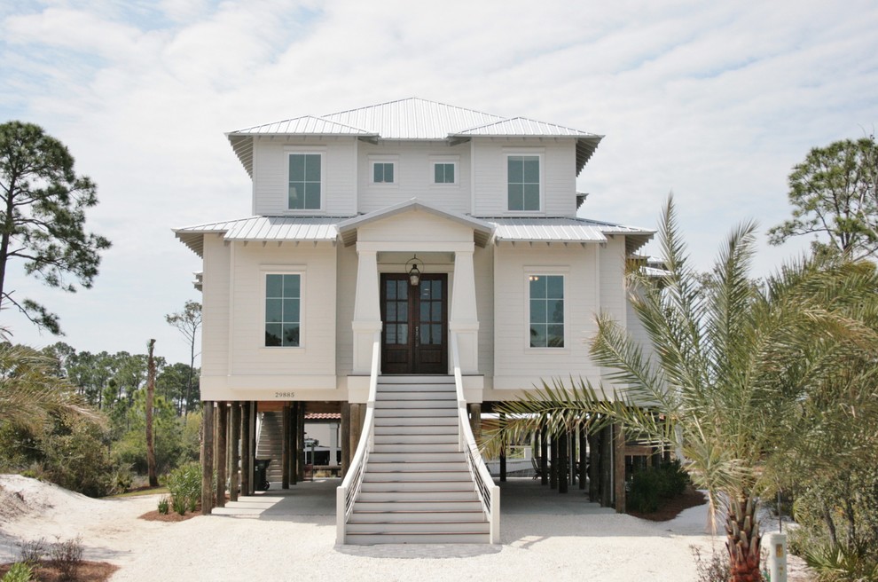 This is an example of a mid-sized beach style two-storey white exterior in Miami with wood siding and a hip roof.