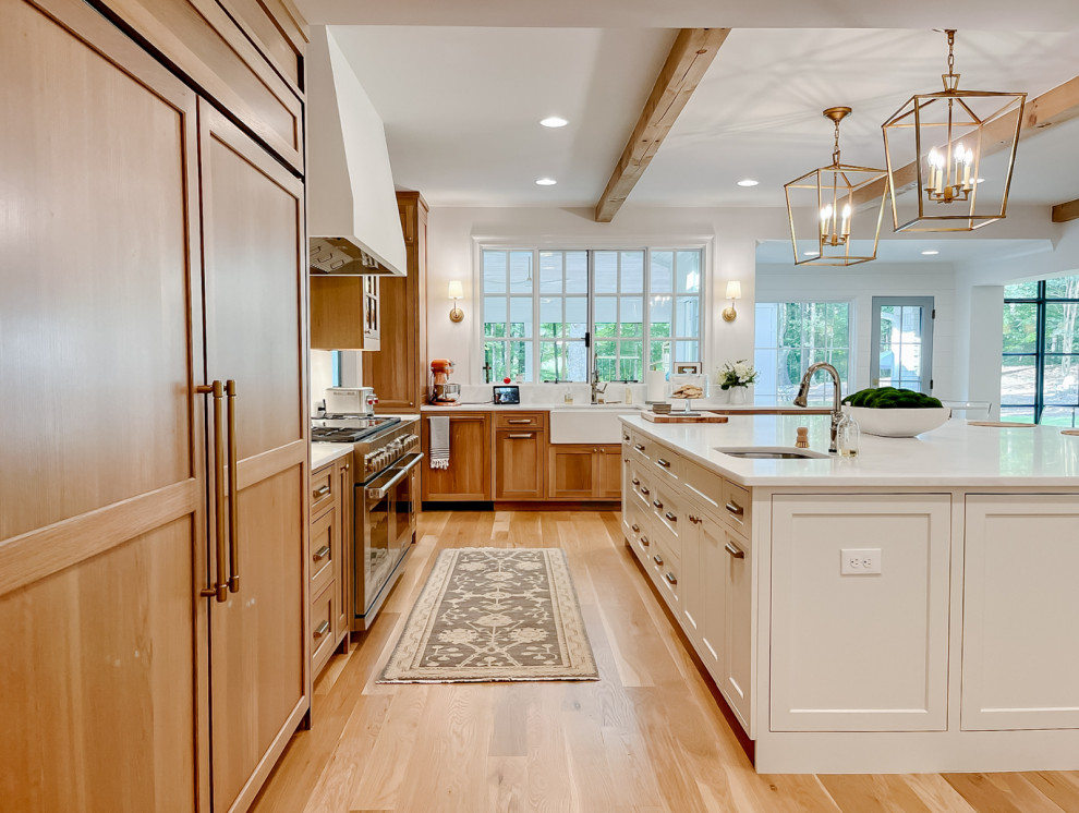 Town + Country Addition and Renovation - Our clients wanted a kitchen that could keep up with their family's pace. They love watching cooking competitions and wanted their kitchen to be the perfect spot for their kids to have cookie bake-offs. To make that possible, their kitchen needed to be wider, more capable, and more open than their current one, while still feeling connected to the family room. The wife wanted to be present with her family even while cooking, with a clear view of both the breakfast room and the family room wherever she stood. That sightline became the guiding principle for the entire space.

What came together is nothing short of a dream kitchen. The footprint was dramatically expanded as part of the addition, anchored by an oversized island with a bright quartz countertop that invites the whole family to pull up a stool and stay a while. Warm, natural wood cabinetry wraps the perimeter, grounding the space with richness and texture, while the white island keeps everything feeling bright and open. Exposed wood beams overhead carry warmth upward, and a pair of brass lantern pendants over the island add just the right amount of drama without competing with the natural light pouring in through the wall of windows in the breakfast room.

The butler's pantry, tucked just off the kitchen, adds the kind of storage and prep space that makes a busy household run smoothly, and gives the whole cooking experience a sense of ease and luxury that the family now wonders how they ever lived without. And with the family room and breakfast room always in view, separated only by open air, this kitchen doesn't just function beautifully. It draws everyone together exactly the way our clients always hoped it would.