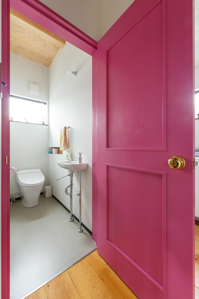 This is an example of an industrial powder room in Other with a one-piece toilet, white walls and a console sink.