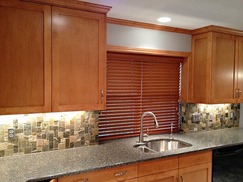 Kitchen - transitional kitchen idea in Austin with a double-bowl sink, medium tone wood cabinets, granite countertops, green backsplash, stone tile backsplash, stainless steel appliances and no island