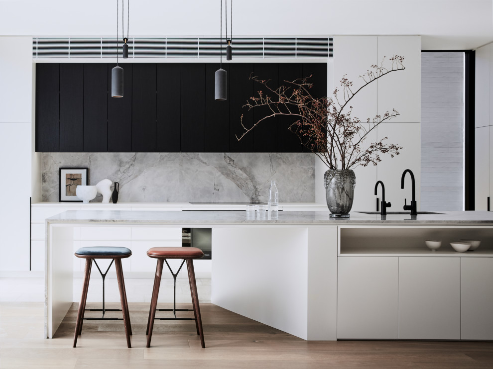 Inspiration for a large contemporary l-shaped open plan kitchen in Sydney with a double-bowl sink, flat-panel cabinets, white cabinets, marble benchtops, grey splashback, marble splashback, black appliances, medium hardwood floors, with island, brown floor and grey benchtop.