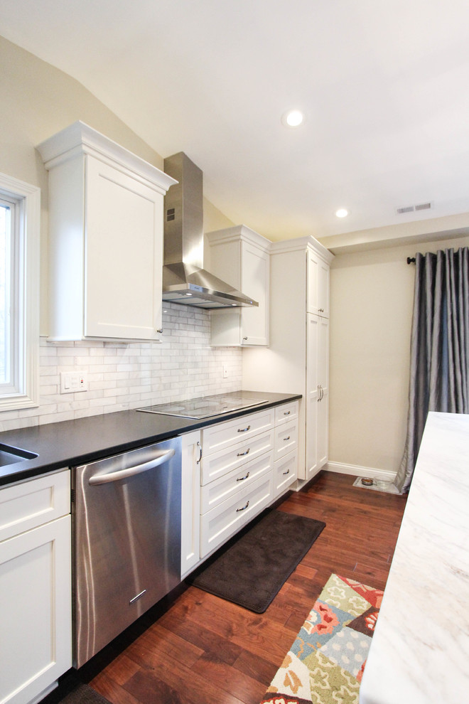 Eat-in kitchen - mid-sized transitional l-shaped medium tone wood floor eat-in kitchen idea in Cincinnati with an undermount sink, recessed-panel cabinets, white cabinets, quartzite countertops, white backsplash, subway tile backsplash, stainless steel appliances and an island
